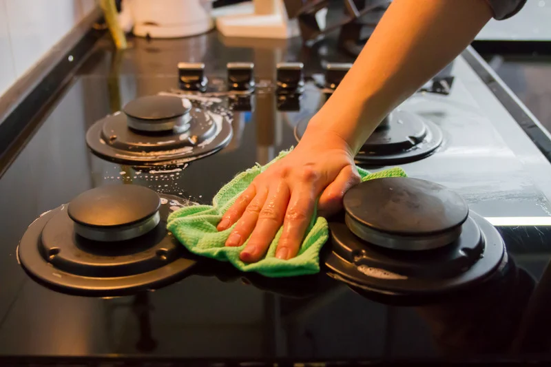 Cleaning cloth wiping down stovetop burners in detail